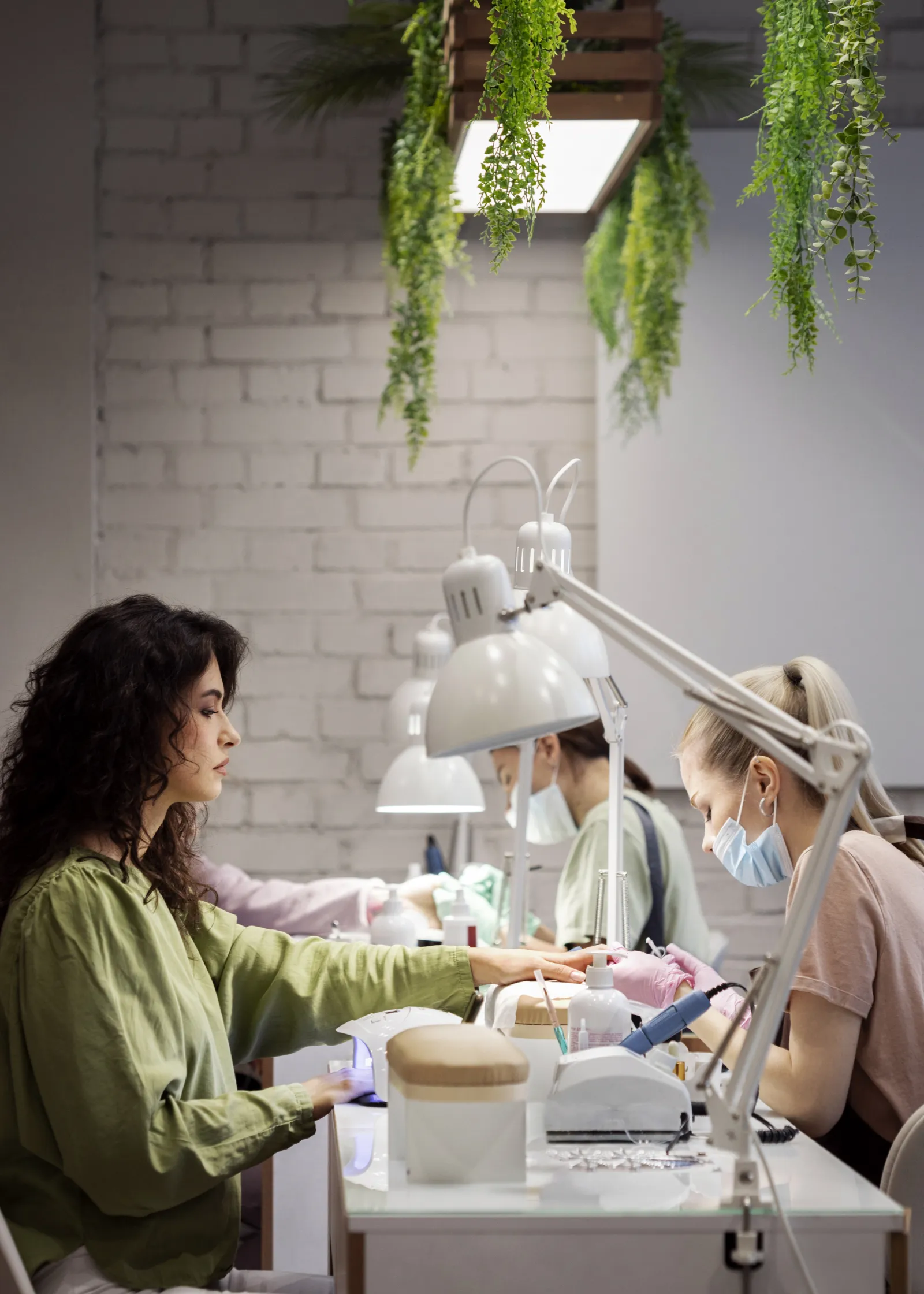 A nail artist working carefully on a client's nails at a salon desk under bright light