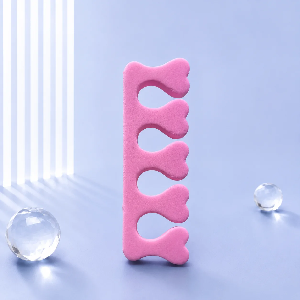 A single VIRAA pink foam toe separator standing upright, showing its five heart-shaped toe openings